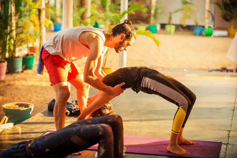 A man and woman practicing yoga in the sun during a 50 hr yoga ttc in Goa