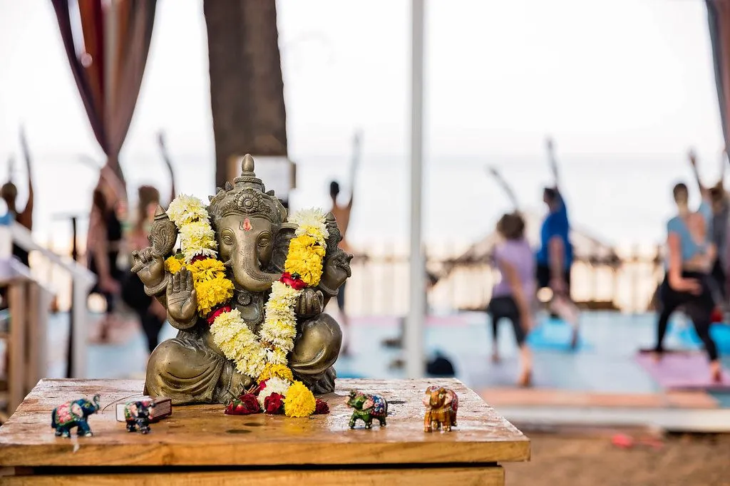 Yoga ttc in Goa, India: Elephant statue on table with people doing yoga